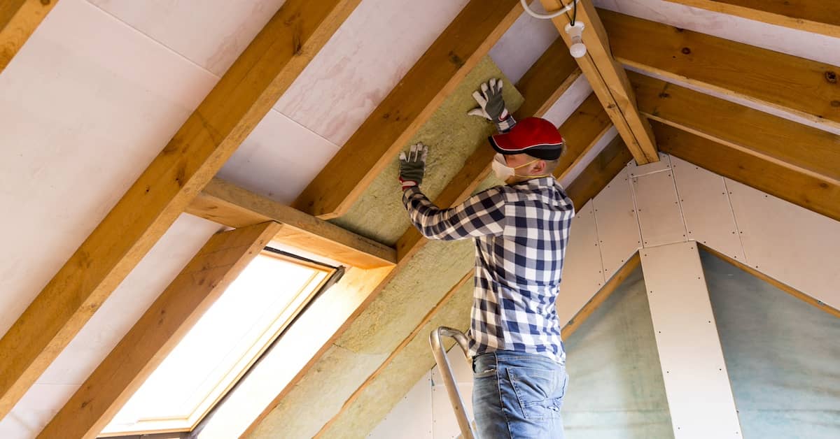 Man installing insulation in the roof of an attic | REenergizeCO