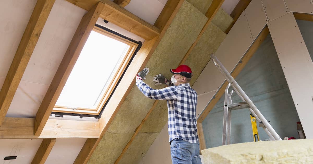 Man installing attic insulation to seal attic air leaks | REenergizeCO