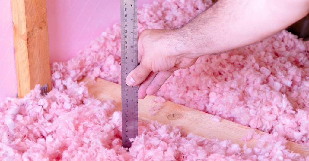 man measuring the energy efficiency of blown-in fiberglass insulation